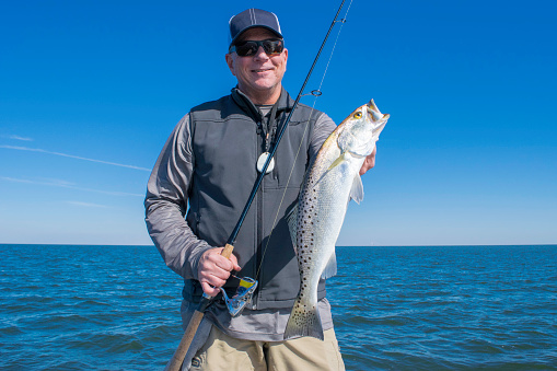 A fisherman holding a large speckled sea trout.