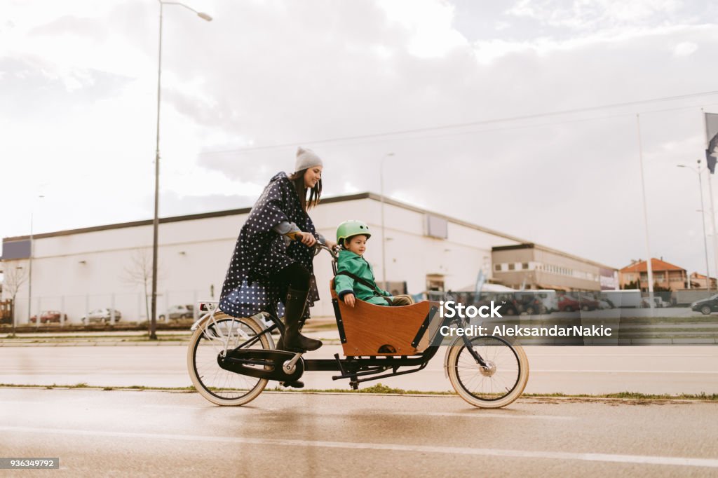 Cargo bike ride on the rain Mother and son having a ride with cargo bike on the rain Cargo Bike Stock Photo