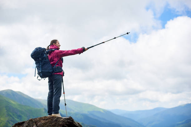 istock Full length of a female backpacker pointing away with her trekking pole copyspace direction navigation location hiking camping travelling backpacking lifestyle hobby exploring activity. 936350644