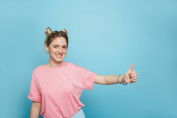 istock modern young woman on a blue background, thumbs up 936352518