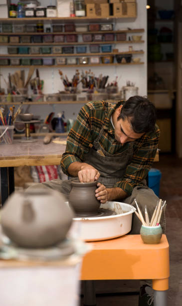 istock Male artist makes clay pottery on a spin wheel 936353612
