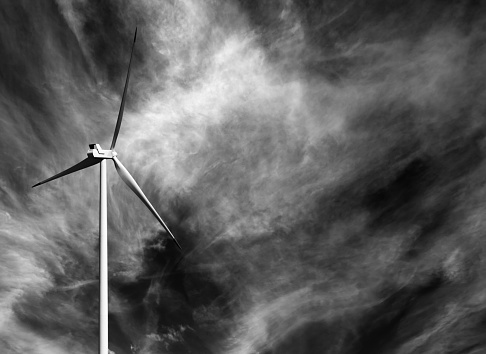 Wind turbine and black and white sky with clouds at windy day
