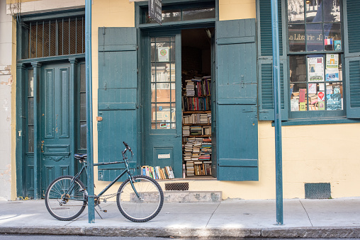 New Orleans, LA, January 23, 2018: Beautiful scene in the French Quarter - A bicycle is parked outside a booktore with books lined on shelves at the window. Typical architecture for the French Quarter