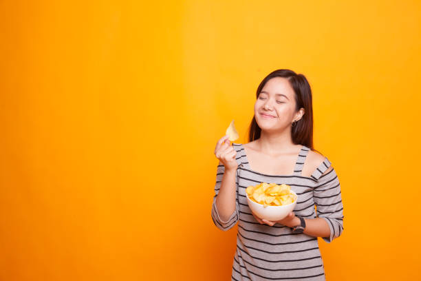 istock Young Asian woman eat potato chips. 936374396