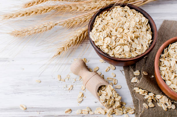 istock Oat flakes  in ceramic bowl and wooden spoon and spikelets 936378910