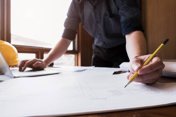 istock young engineers are writing modern project on blueprints in the office, Engineer concept 936379602