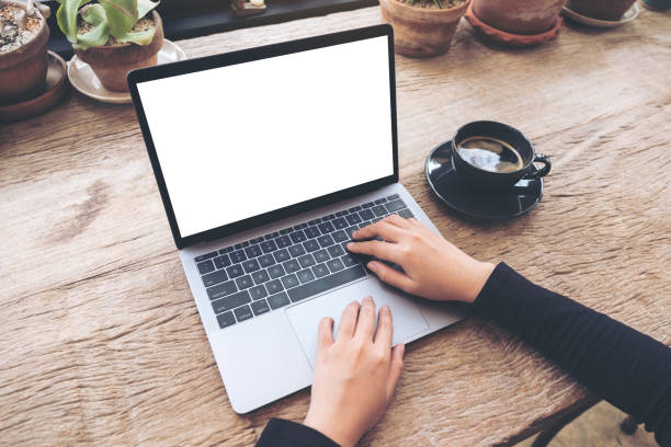 istock Top view mockup image of hands using and typing on laptop with blank white desktop screen on vintage wooden table in cafe 936382938