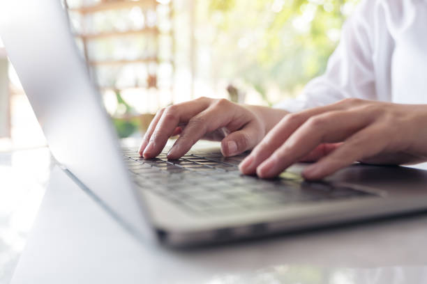 istock Closeup image of hands working and typing on laptop keyboard on table with blur nature background 936383244