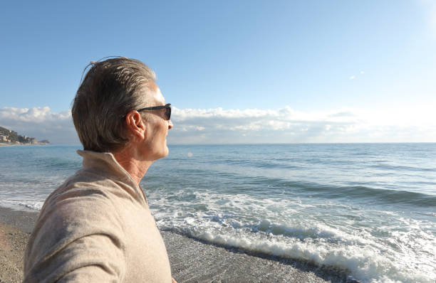 istock Man looks off to sea on sunny day 936383440