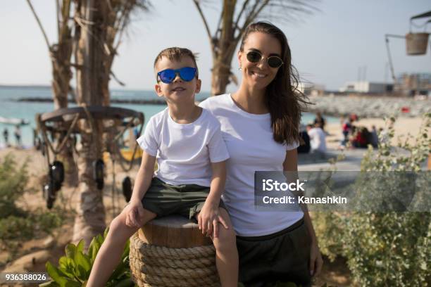 Woman With Her Son In White Tshirts Standing On The Beach Stock Photo - Download Image Now