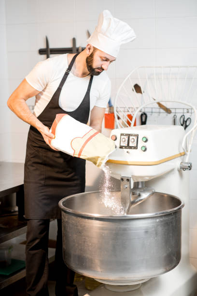 istock Baker filling flour into the kneader 936388480