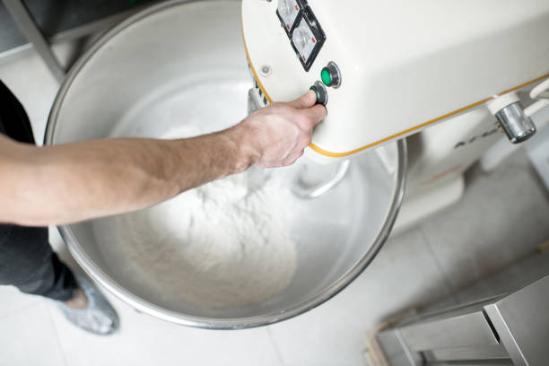 Mixing a dough for bread baking with professional kneader machine at the manufacturing