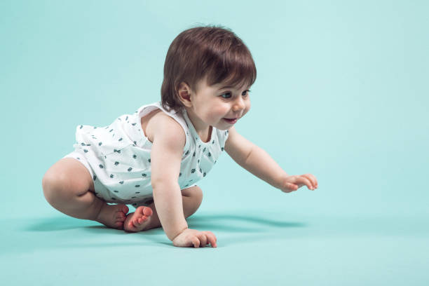 istock Cute small girl crawling sitting in studio on blue background 936390444