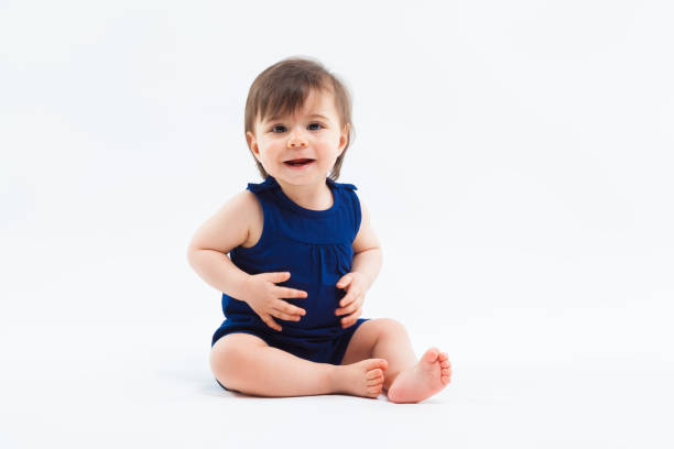 istock Cute funny small smiling girl sitting in studio posing on white background 936390540
