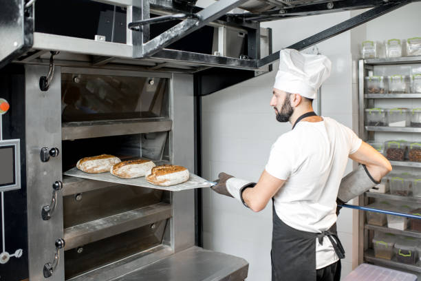 istock Baker taking off the breads from the oven 936392320