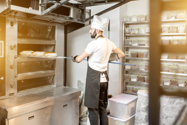 istock Baker taking off the breads from the oven 936392342