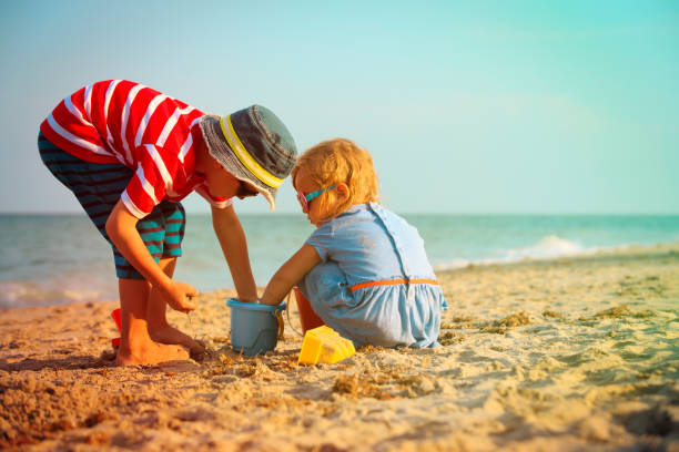 istock little boy and girl play with sand on beach 936393474