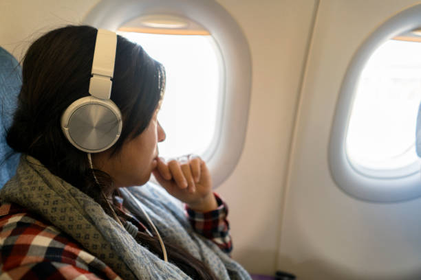 istock girl sitting beside window on plane 936397218