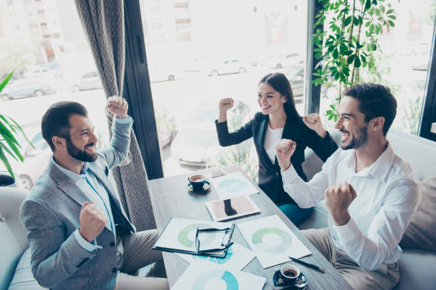 istock Success and team work concept. Group of business partners with raised up hands in light modern terrace of a fancy restaurant, celebrating the breakthrough in their company 936397746