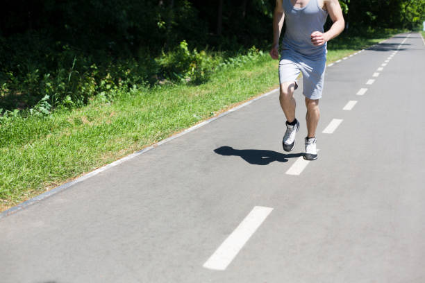 istock Young man jogging on treadmill in park, copy space 936398418