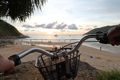 POV past hands on handlebars and basket to beach at sunrise.
