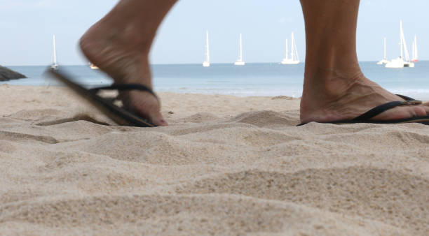 низкий урожай ног в сандалиях, идущих по песку. - flip flop human foot sand women стоковые фото и изображения