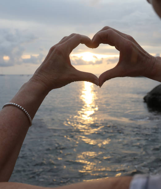 istock Hands shape heart against sunset and sea 936398788