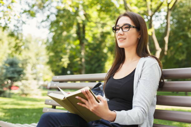 istock Young woman reading book in park copy space 936401006