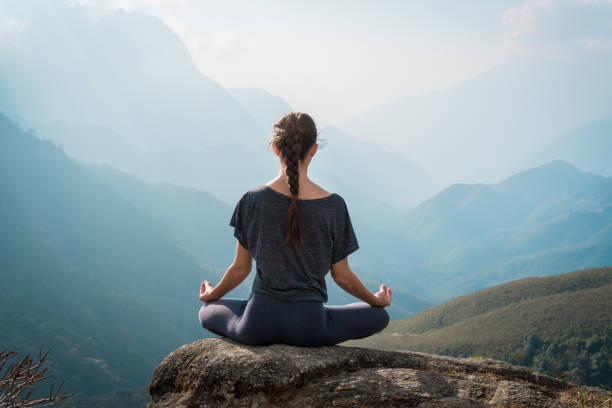 Woman meditates in yoga asana Padmasana Woman meditates in yoga asana Padmasana - Lotus pose on mountain cliff sitting position stock pictures, royalty-free photos & images