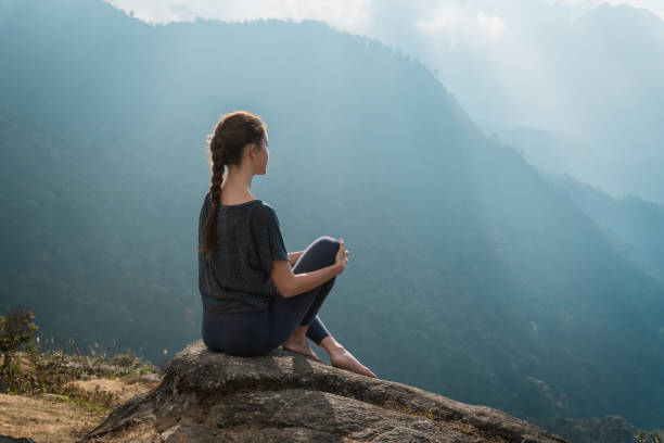 istock Woman sits on mountain cliff 936401382