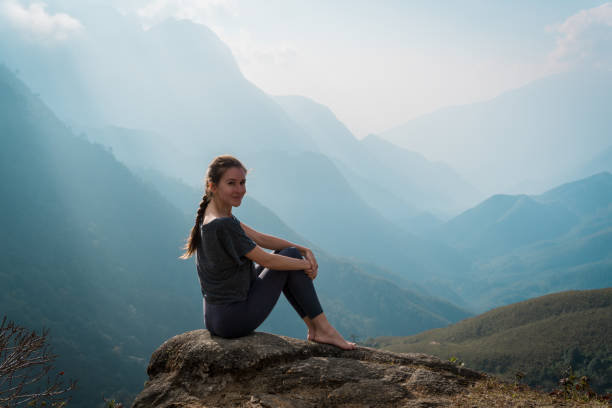 istock Woman sits on mountain cliff 936401422
