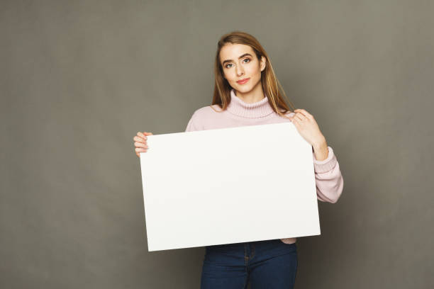 istock Young smiling woman with blank white paper 936404074