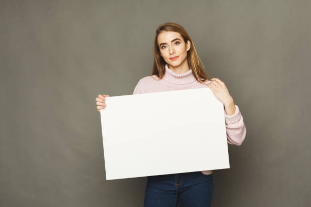 Young smiling woman with blank white paper Young woman with blank white paper. Attractive smiling girl holding advertising sheet, copy space female likeness photos stock pictures, royalty-free photos & images