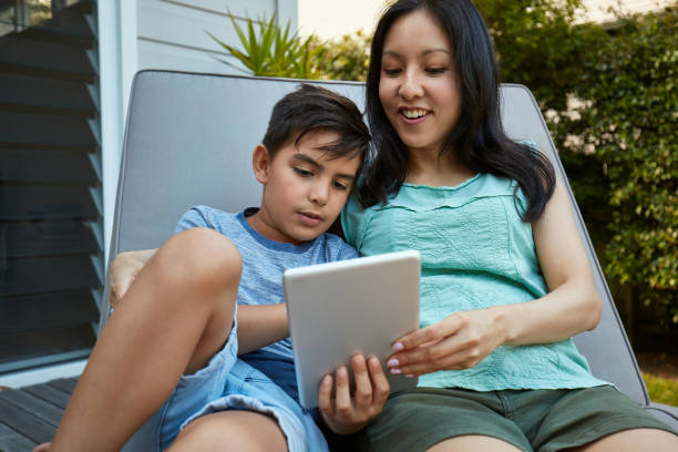 istock Son showing mother some school work at digital tablet outdoors 936404772
