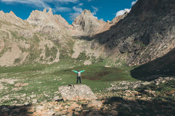 istock Cheering woman hiker with backpack hiking on high altitude mountain 936406160