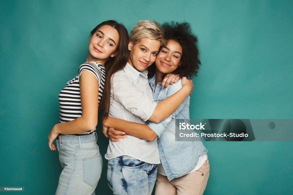 Friends having fun at blue background Happy female friends having fun at blue background. Three young women having friendly talk, gossiping and laughing, slumber party, copy space Friendship Stock Photo