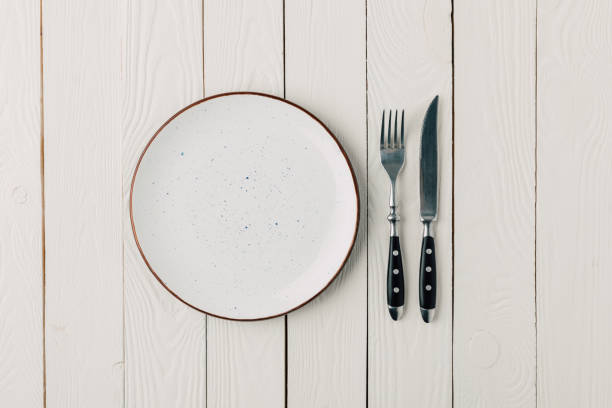 istock Empty plate and cutlery on white wooden background 936407394