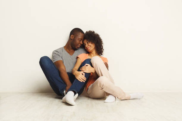 istock African-american couple hugging, sitting on floor 936409232