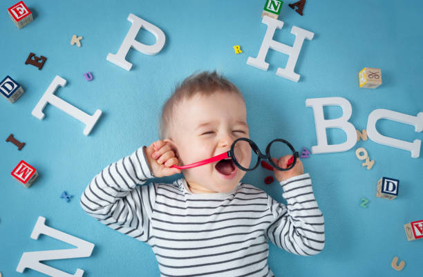 één jaar oud kind liggen met bril en/of letters - alleen babys stockfoto's en -beelden