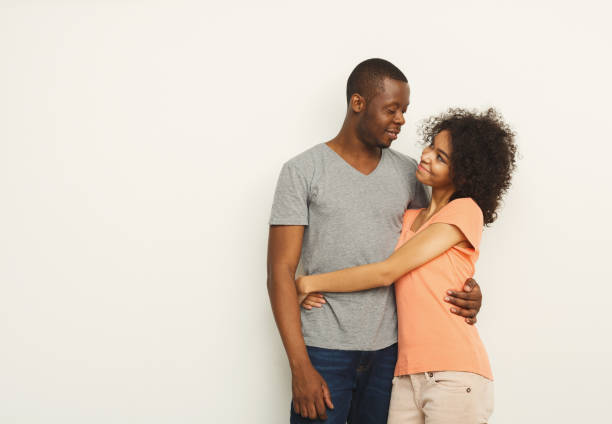istock Smiling black couple embracing at white studio 936409504