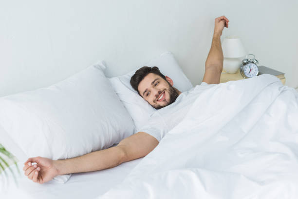 istock happy bearded man stretching in bed in the morning 936410910
