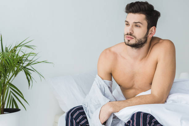 istock handsome thoughtful man taking off his t-shirt in bedroom 936411216
