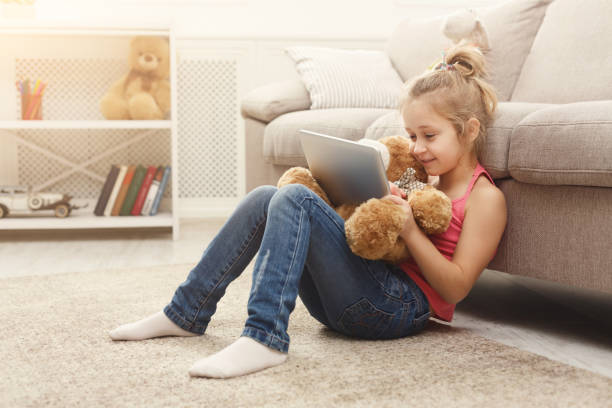 istock Little girl with tablet and teddy bear at home 936414100