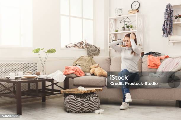 Desperate Woman Sitting On Sofa In Messy Room Stock Photo - Download Image Now - Messy, Domestic Life, House