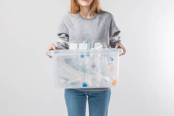 istock partial view of woman holding container with plastic bottles isolated on grey, recycle concept 936417714