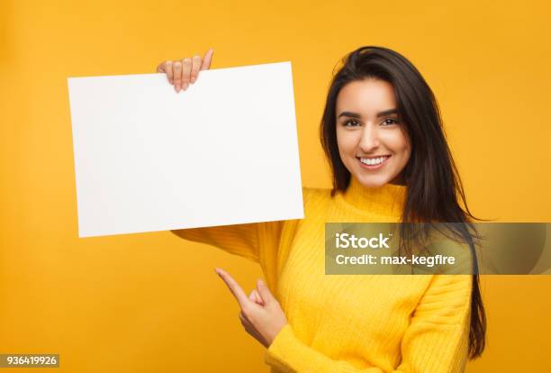 Charming Brunette Pointing At Blank Paper Stock Photo - Download Image Now - Holding, Women, People