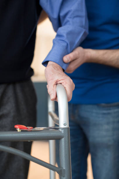 istock Senior Man's Hands On Walking Frame With Care Worker In Background 936420168