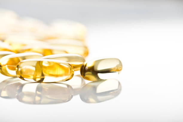 光輝くイエロービタミン e の魚オイルのカプセルを白背景 - nutritional supplement fish oil vitamin pill bottle ストックフォトと画像