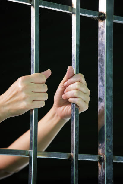 istock hands of prisoner in jail background. 936426442