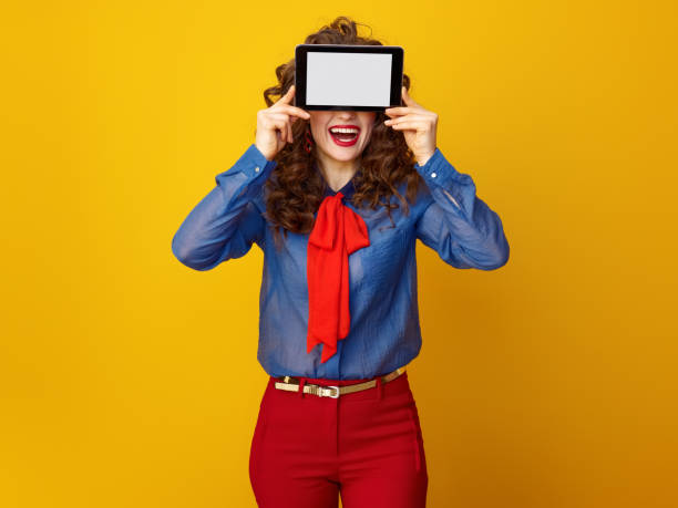 istock happy stylish woman hiding behind tablet PC blank screen 936427396